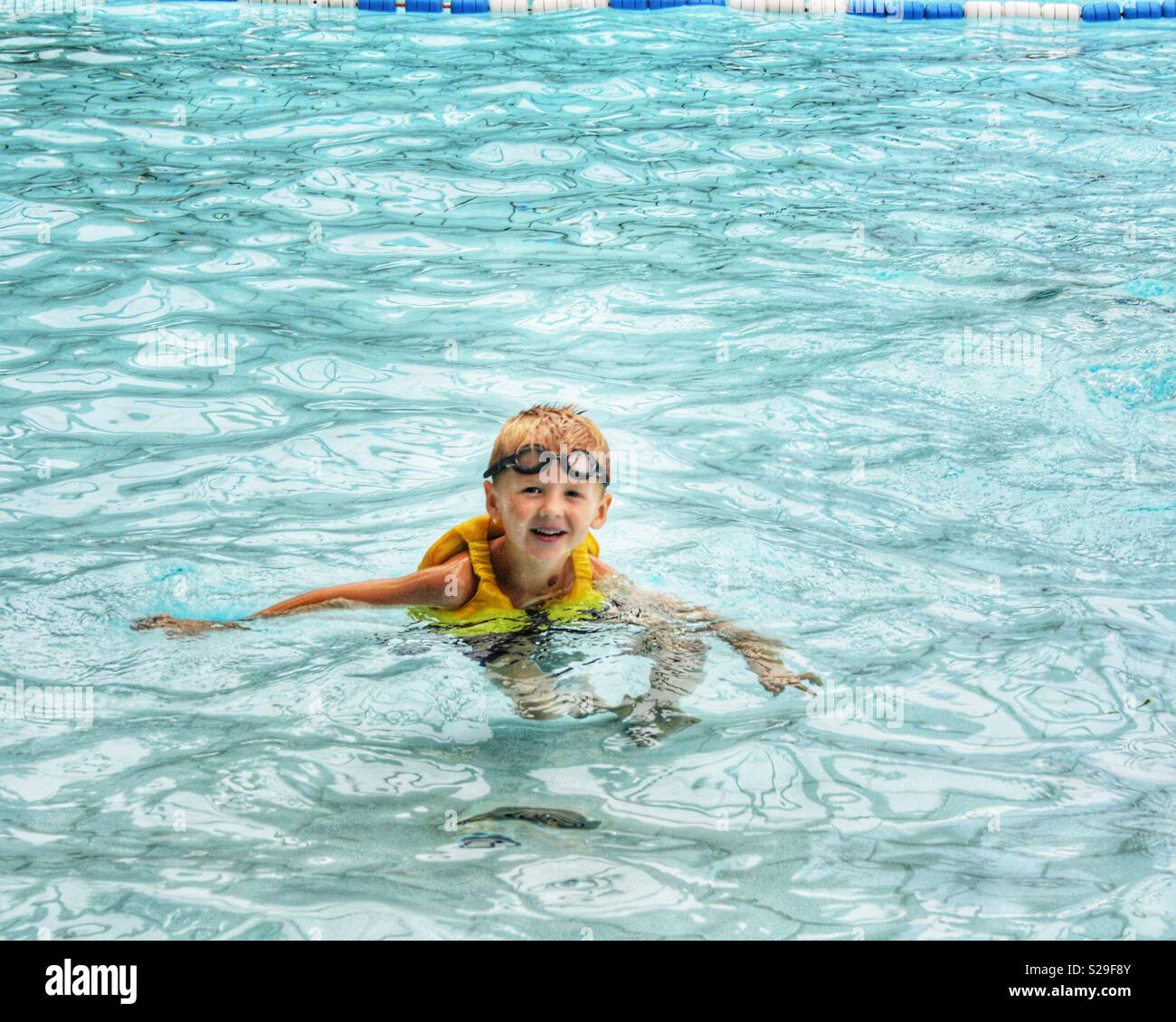 Little boy swimming with goggles & life jacket Stock Photo Alamy
