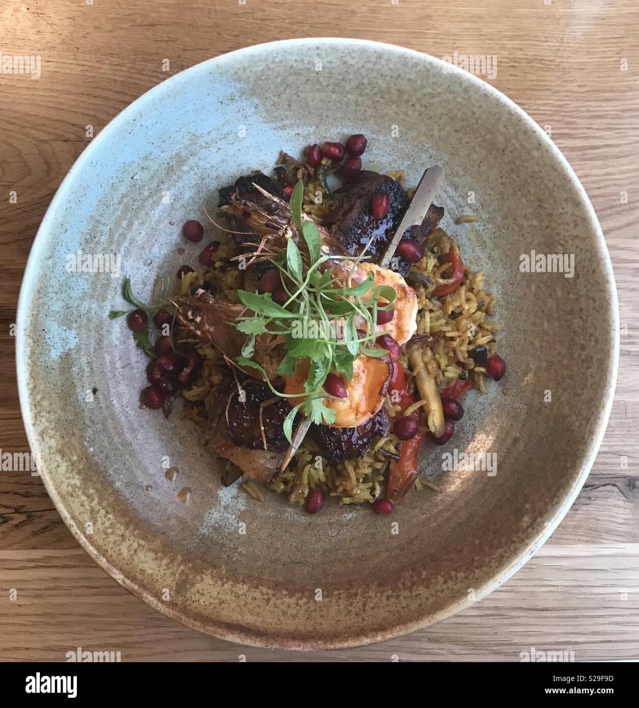 Char siu pork belly, barbecued king prawn, spiced vegetable rice, pomegranate, garlic and lemon dressing at the Admiral, St David’s Hotel, Cardiff Bay, Wales. Stock Photo