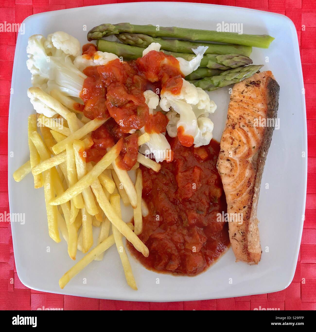 Vegetarian meal of salmon steak, ratatouille, asparagus, cauliflower and French fries on a square plate seen from above - Smartphone Captured Stock Image