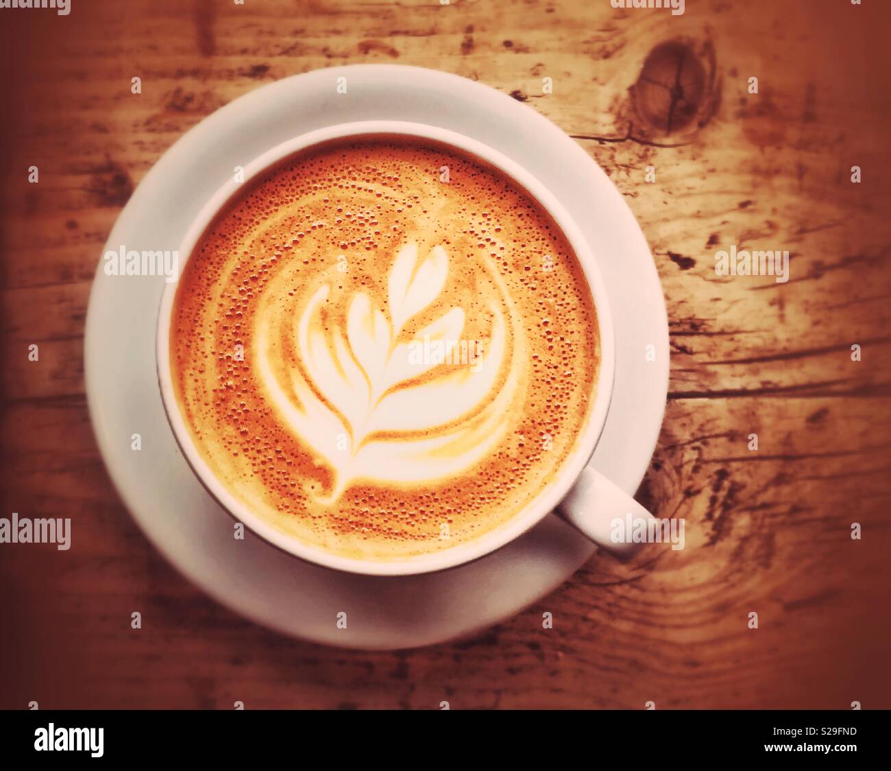 An overhead picture of a large white cup of Latte Coffee. The cup and saucer sit on a wooden table. There is space for copy/text. Photo Credit - © COLIN HOSKINS. - Smartphone Captured Stock Image