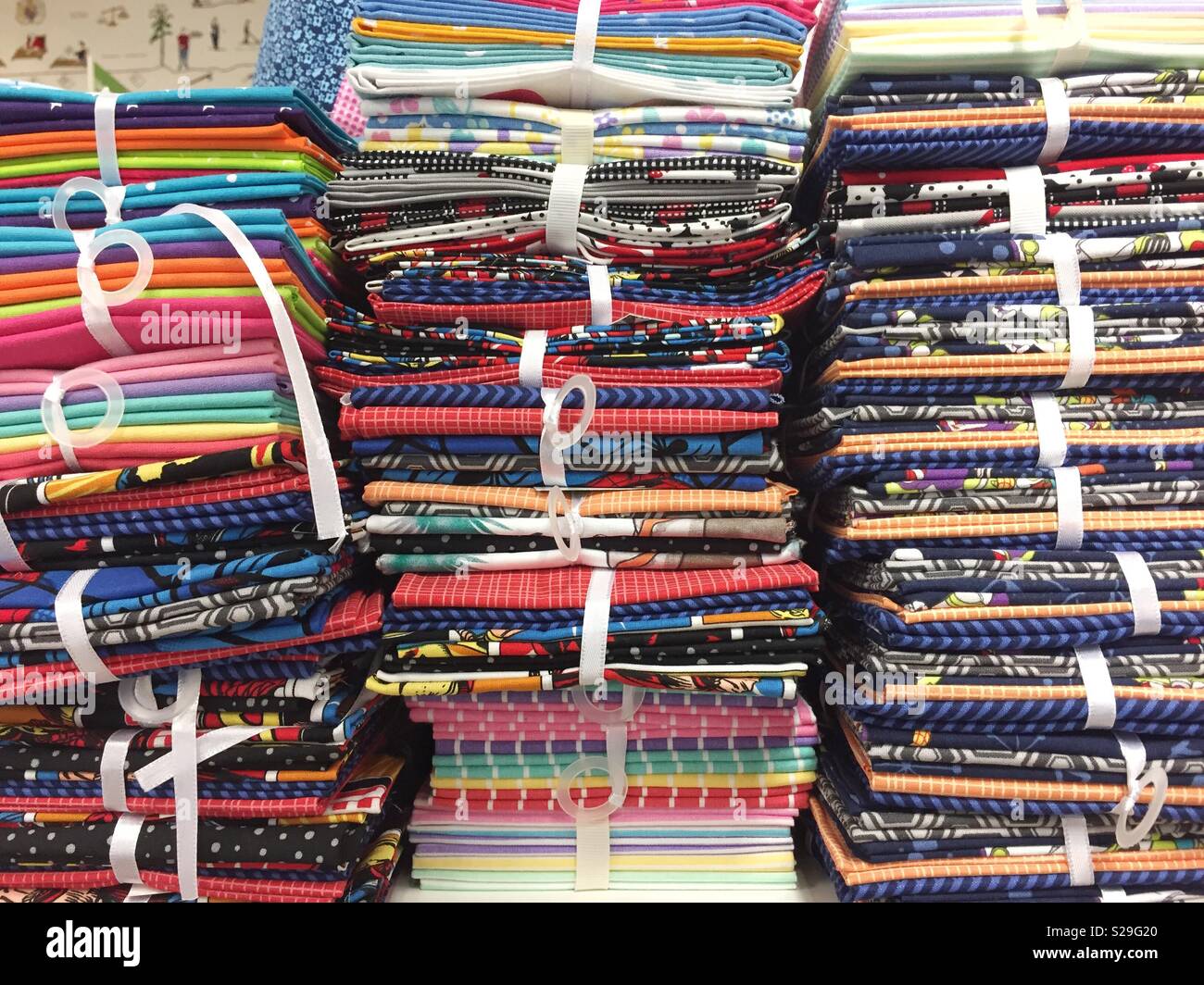 A full frame background of colourful, stacked fabric, textiles and fashion material on a retail store shelf - Smartphone Captured Stock Image