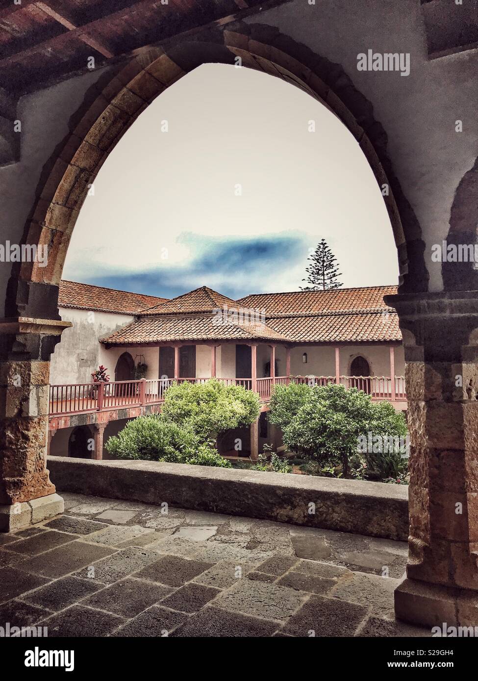 Santa Clara Convent, built for Franciscan Sisters in the 16th Century and still in use today, Funchal, Madeira, Portugal. Courtyard view through cloister arch Stock Photo