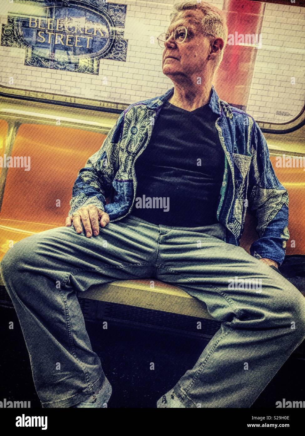 Rude Senior man sitting in a New York City subway and manspreading, USA - Smartphone Captured Stock Image