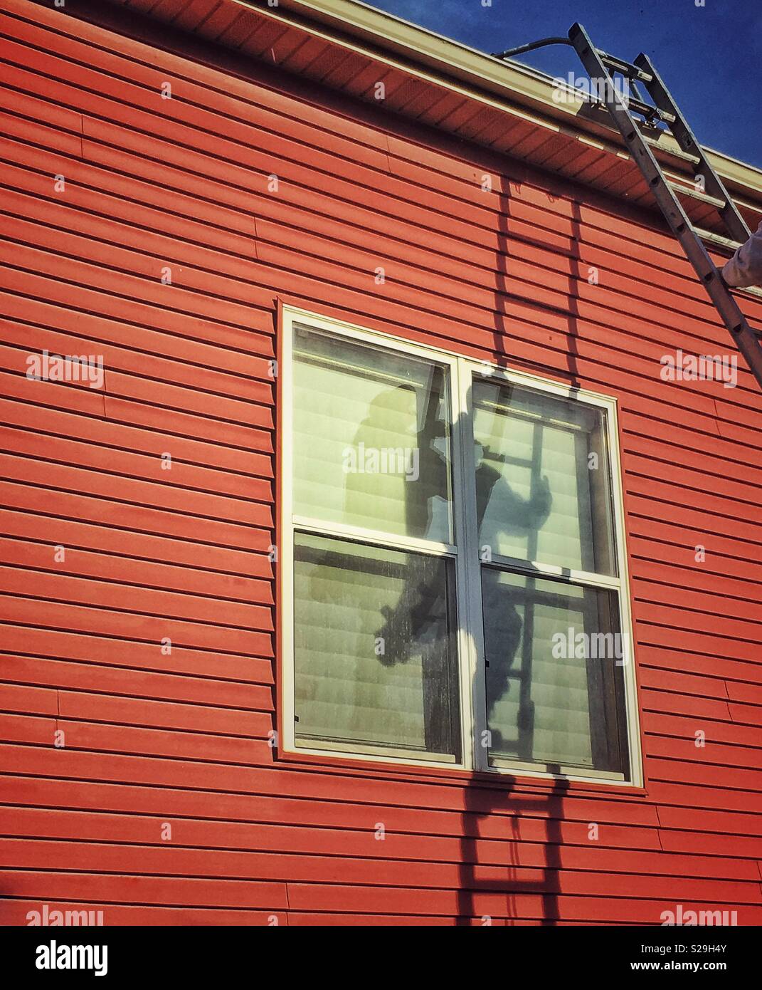 Shadow of a worker climbing a ladder to fix a gutters. - Smartphone Captured Stock Image