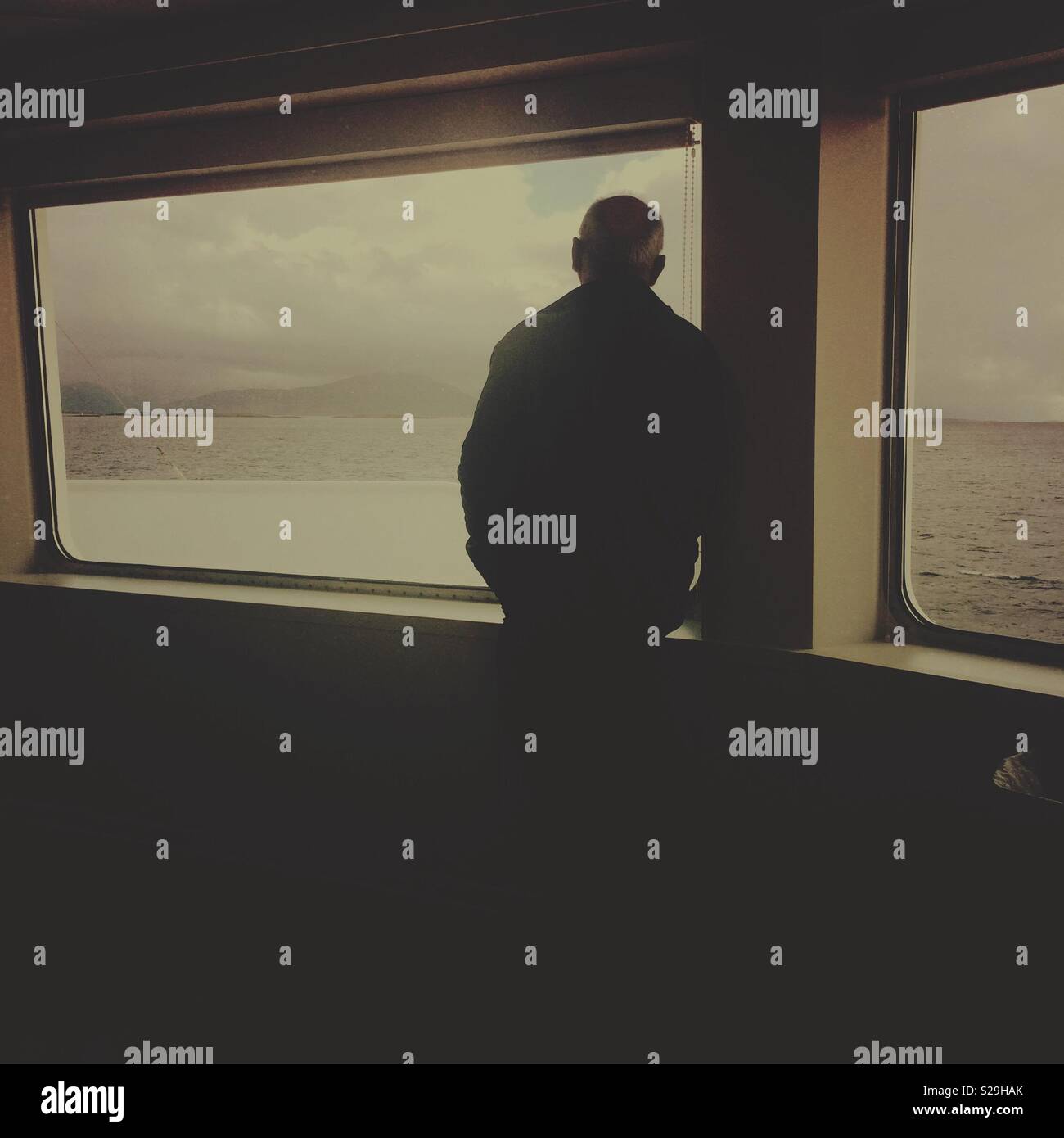 A man and ferry boat window with sea and mountains in the distance - Smartphone Captured Stock Image