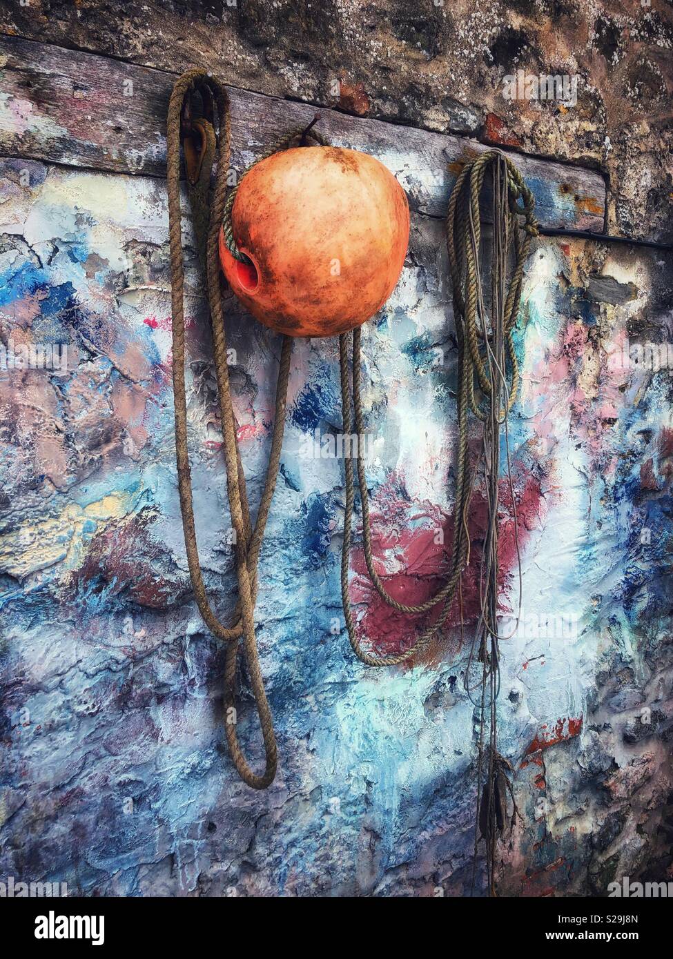 Rope and buoy on a painted boat shed wall, Tenby, West Wales. - Smartphone Captured Stock Image
