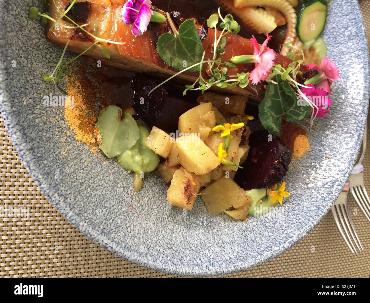 Pork belly grilled and served with an assortment of colorful vegetables and edible flowers at an upmarket restaurant - Smartphone Captured Stock Image