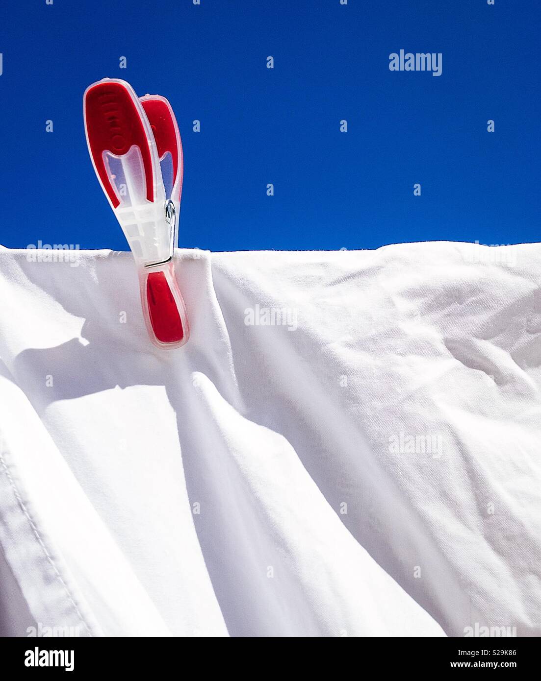 Red, white and blue. Always dreaming of France. White sheet on a washing line with a red peg and a blue sky Stock Photo