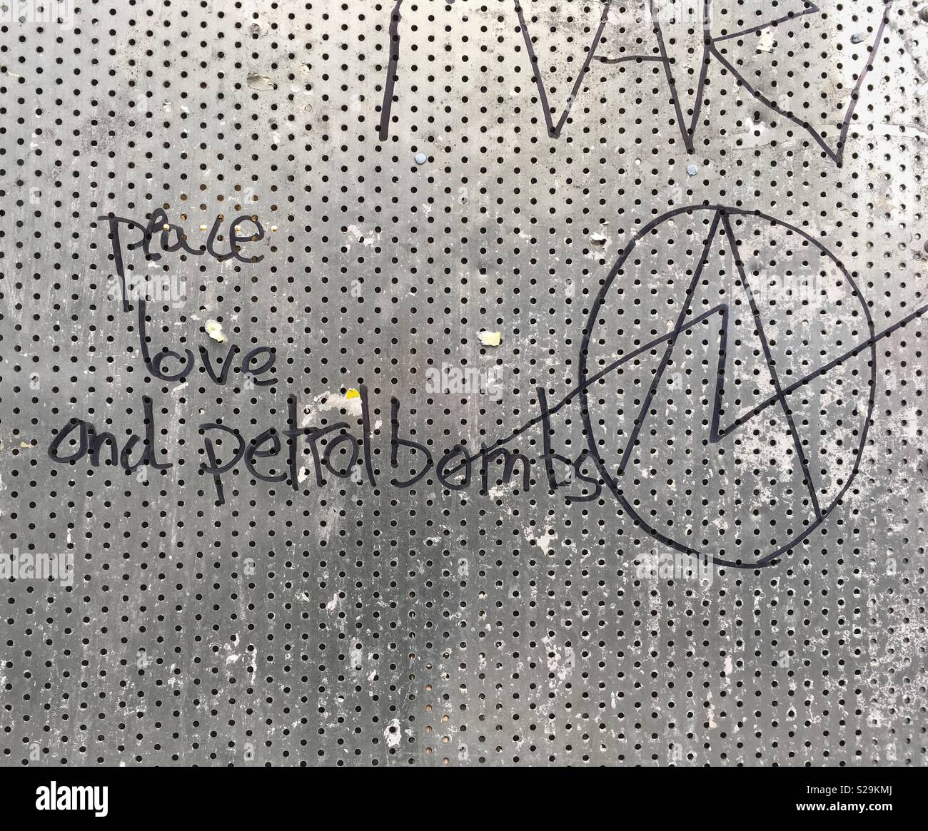 The slogan “peace love and petrol bombs” written on a screen covering the window of an empty shop in Bristol, UK Stock Photo