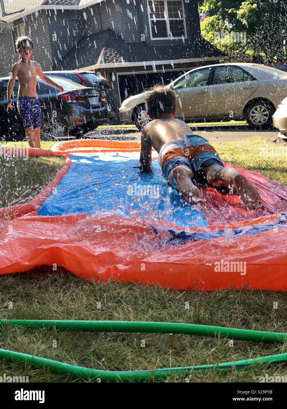 Kids playing on slip and slide on grass Stock Photo Alamy