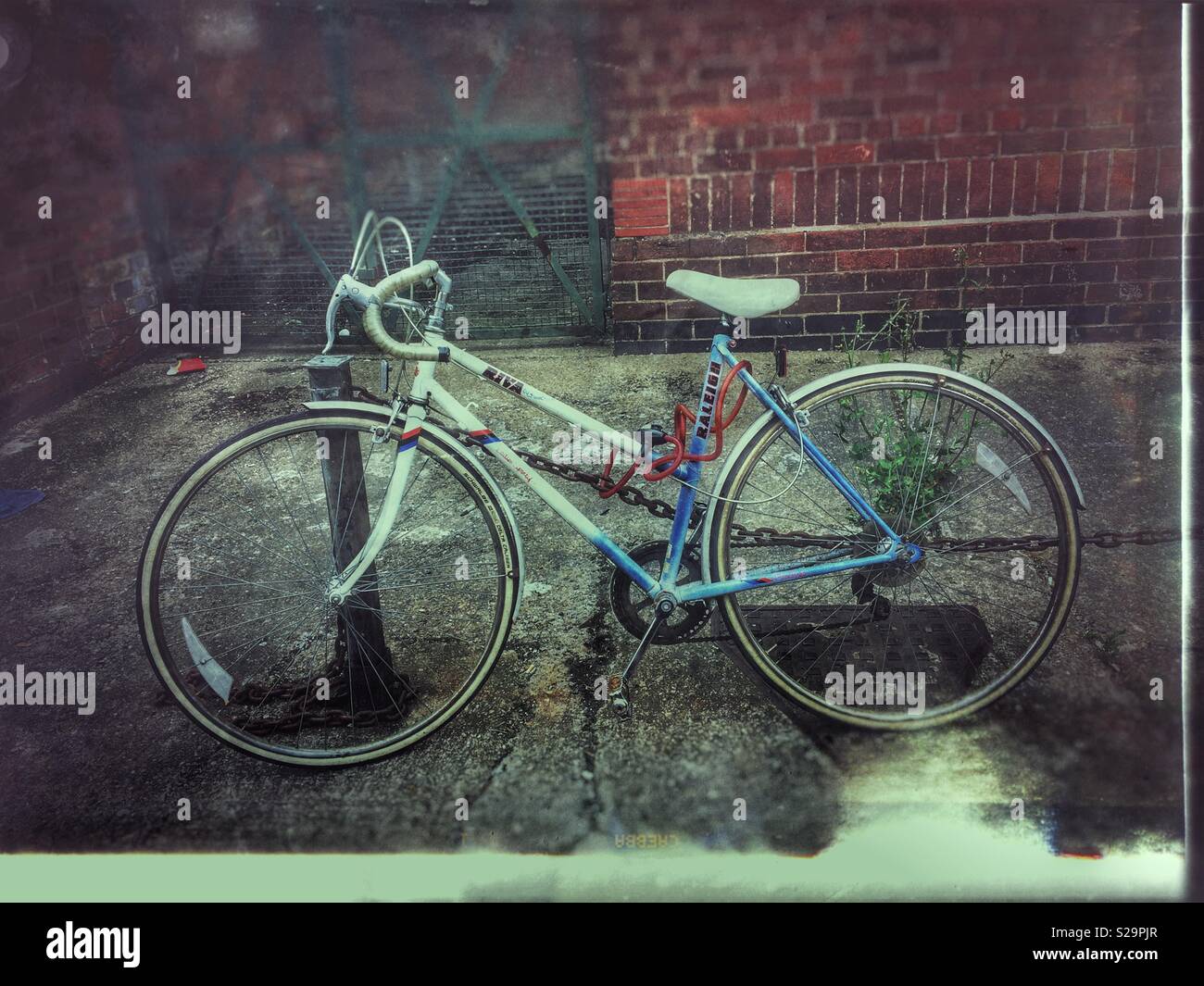 Old bike bicycle locked to bollard England UK - Smartphone Captured Stock Image