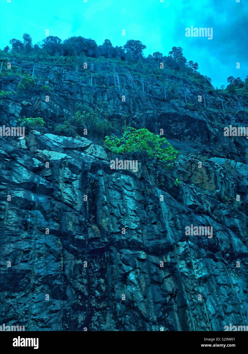 View of rocky topography from a tinted bus window in Malaysia. - Smartphone Captured Stock Image
