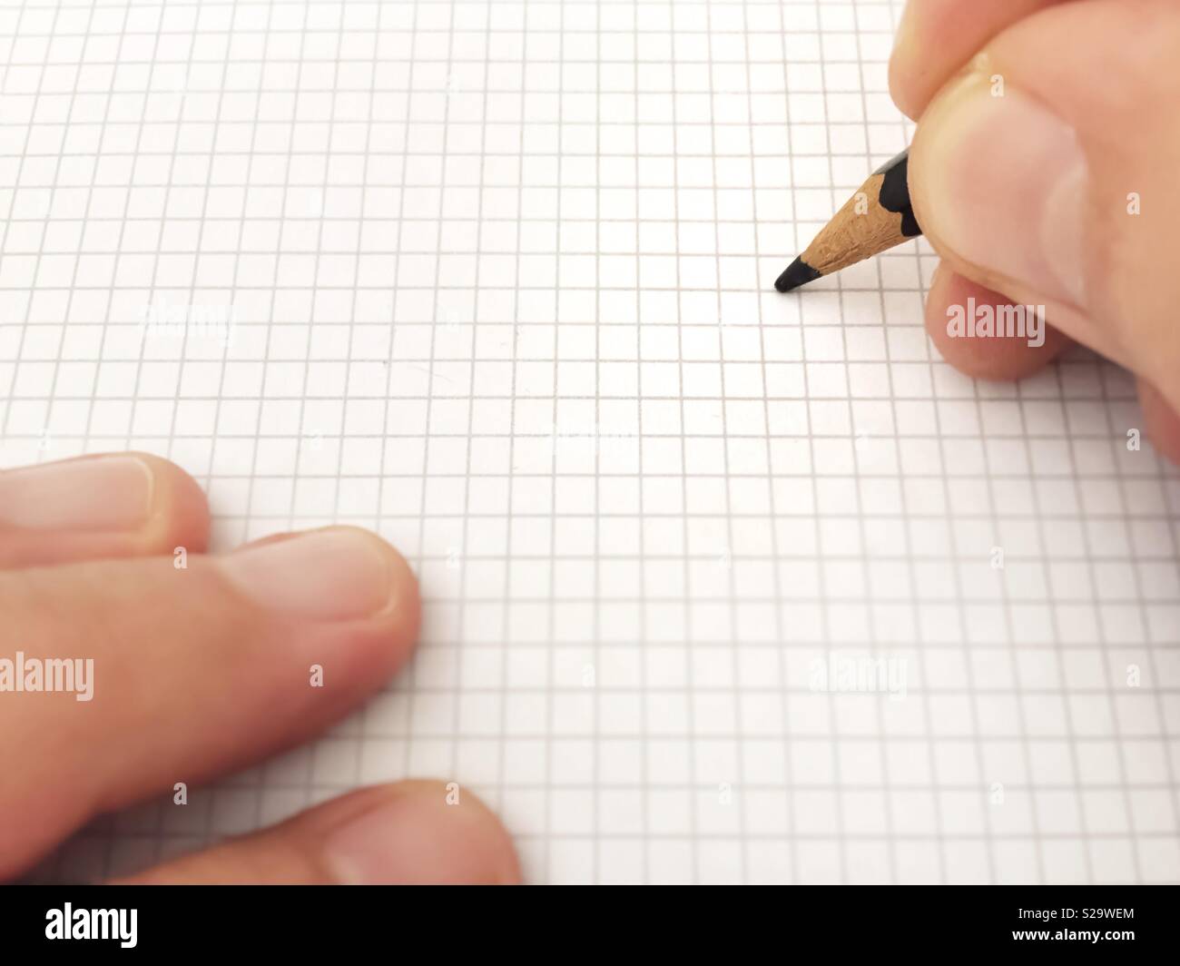 Writing with a pencil on a white sheet of squared paper - Smartphone Captured Stock Image