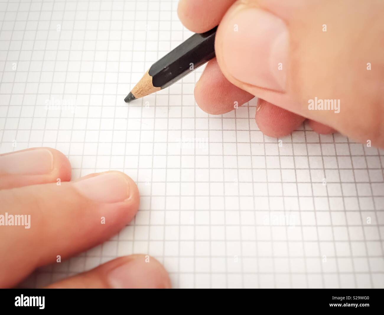 Writing with a pencil on a white sheet of squared paper - Smartphone Captured Stock Image