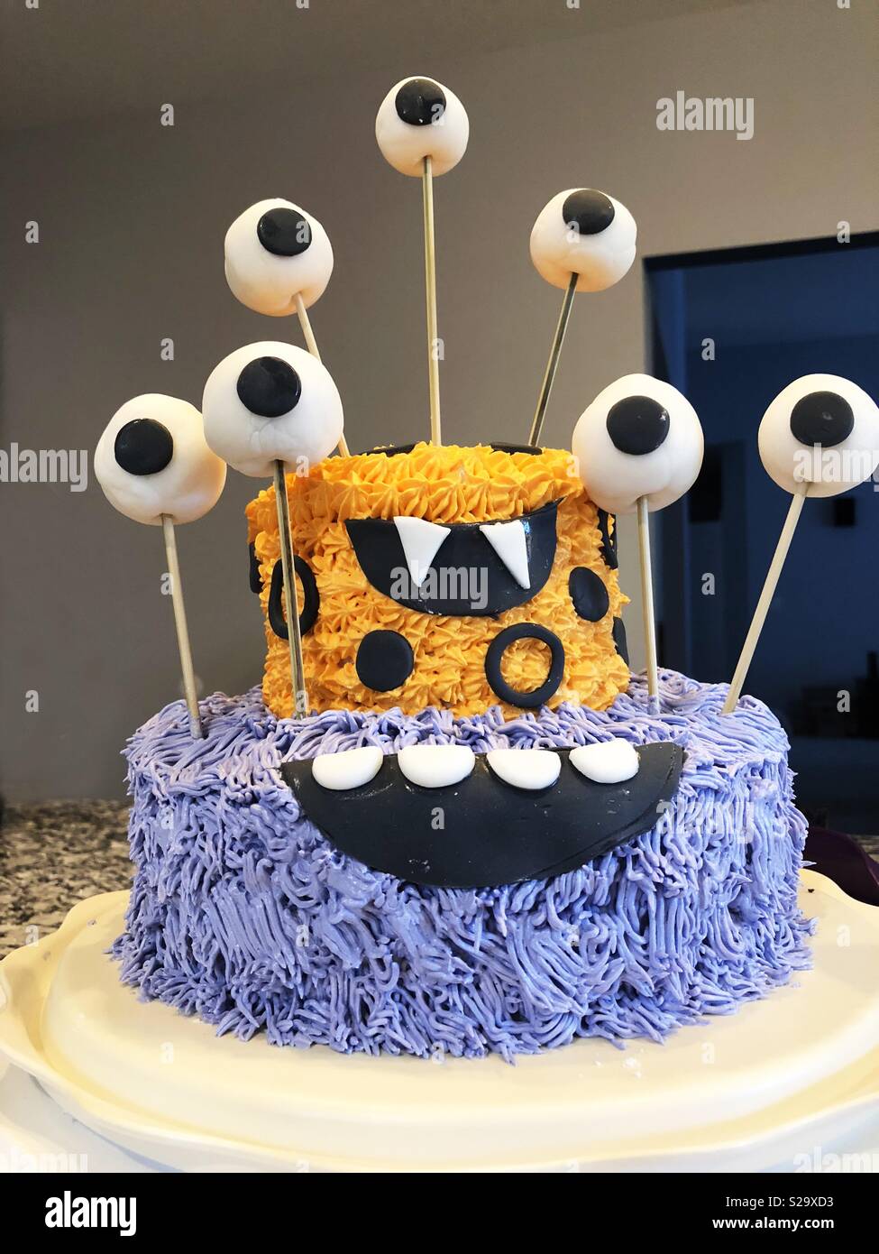 Gold and purple two-layer monster cake with many eyes and piped icing. - Smartphone Captured Stock Image