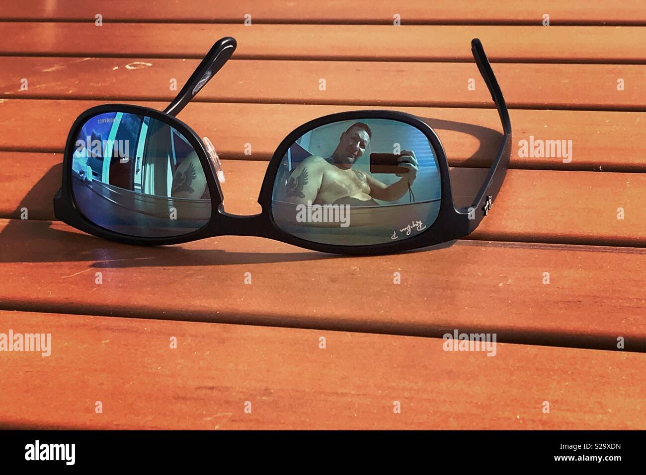 Sunglasses on table top with user in view - Smartphone Captured Stock Image