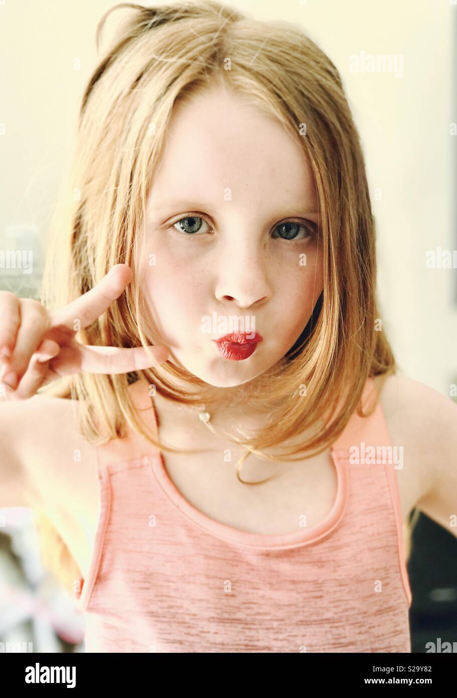 Young girl with pout and v for victory hand gesture Stock Photo