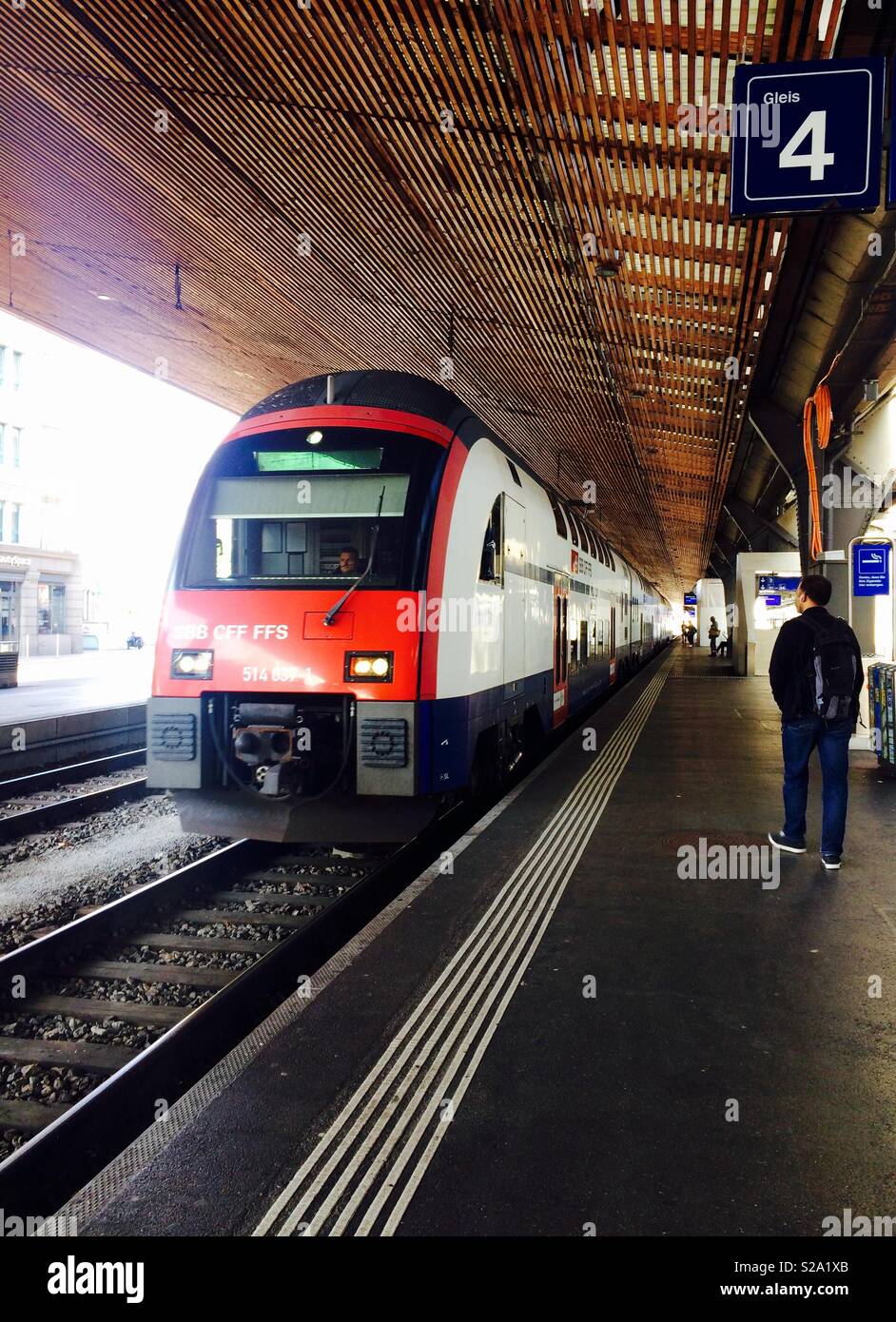 Train arriving at Zurich Hauptbahnhof or main train station in Switzerland with a commuter waiting for the train - Smartphone Captured Stock Image