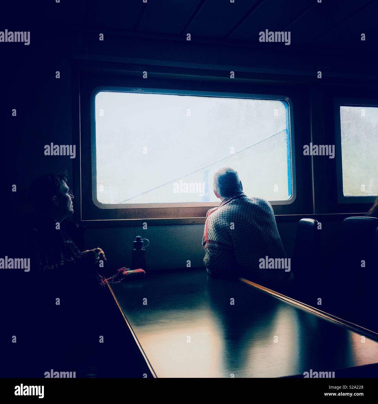 Passengers on a ferry killing time looking out of a window Stock Photo