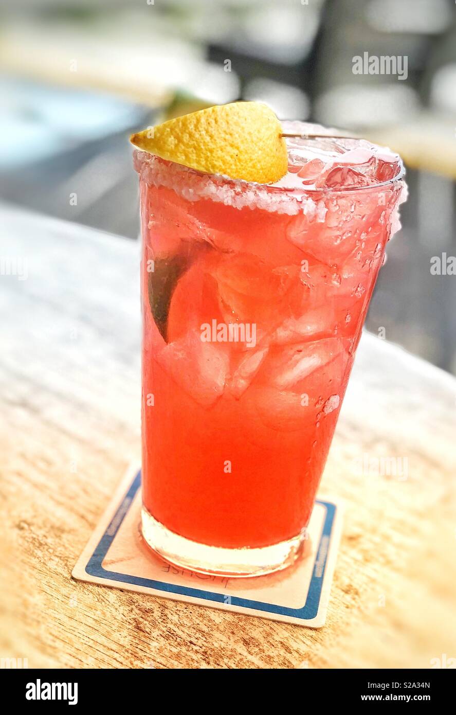 A pomegranate margarita with salt on the glass rim and a lemon - Smartphone Captured Stock Image