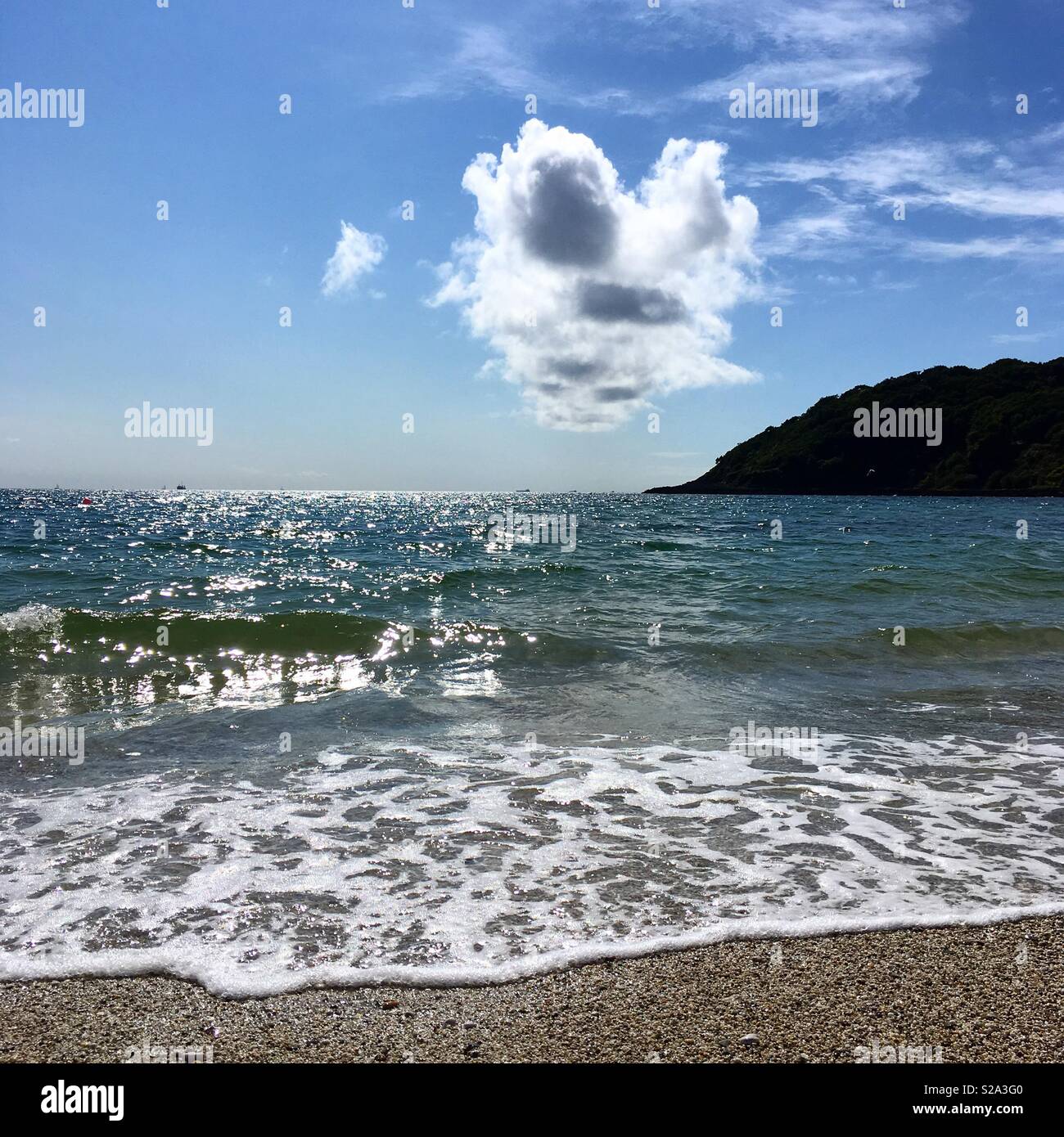 Backlit cloud formation in a blue sky over the sea at Swanpool, Falmouth, Cornwall, UK - Smartphone Captured Stock Image