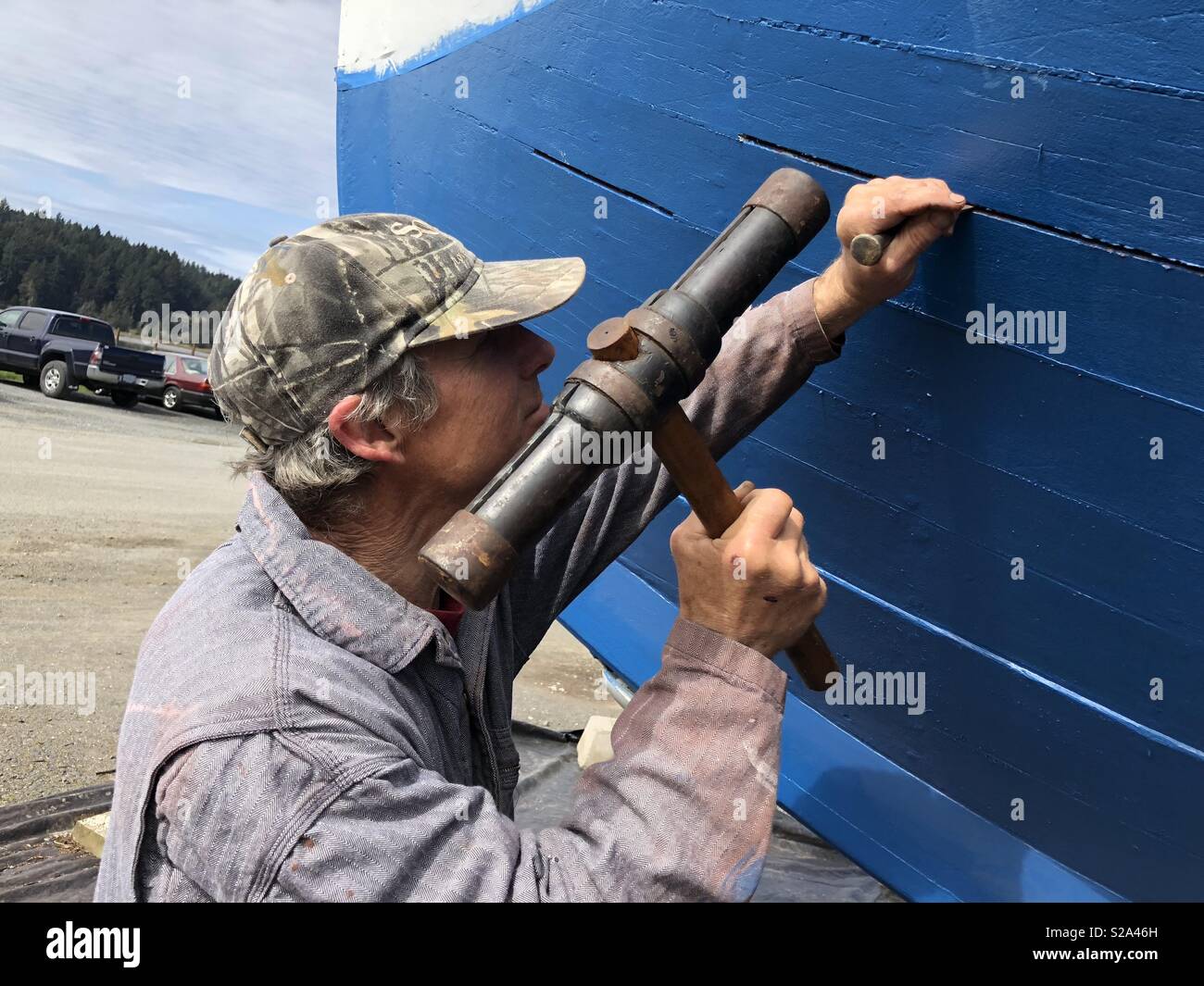 Historic fishing vessel owner and captain demonstrates the use of traditional boatbuilding techniques, materials and tools to maintain his 100 year old wooden fishing boat. Stock Photo