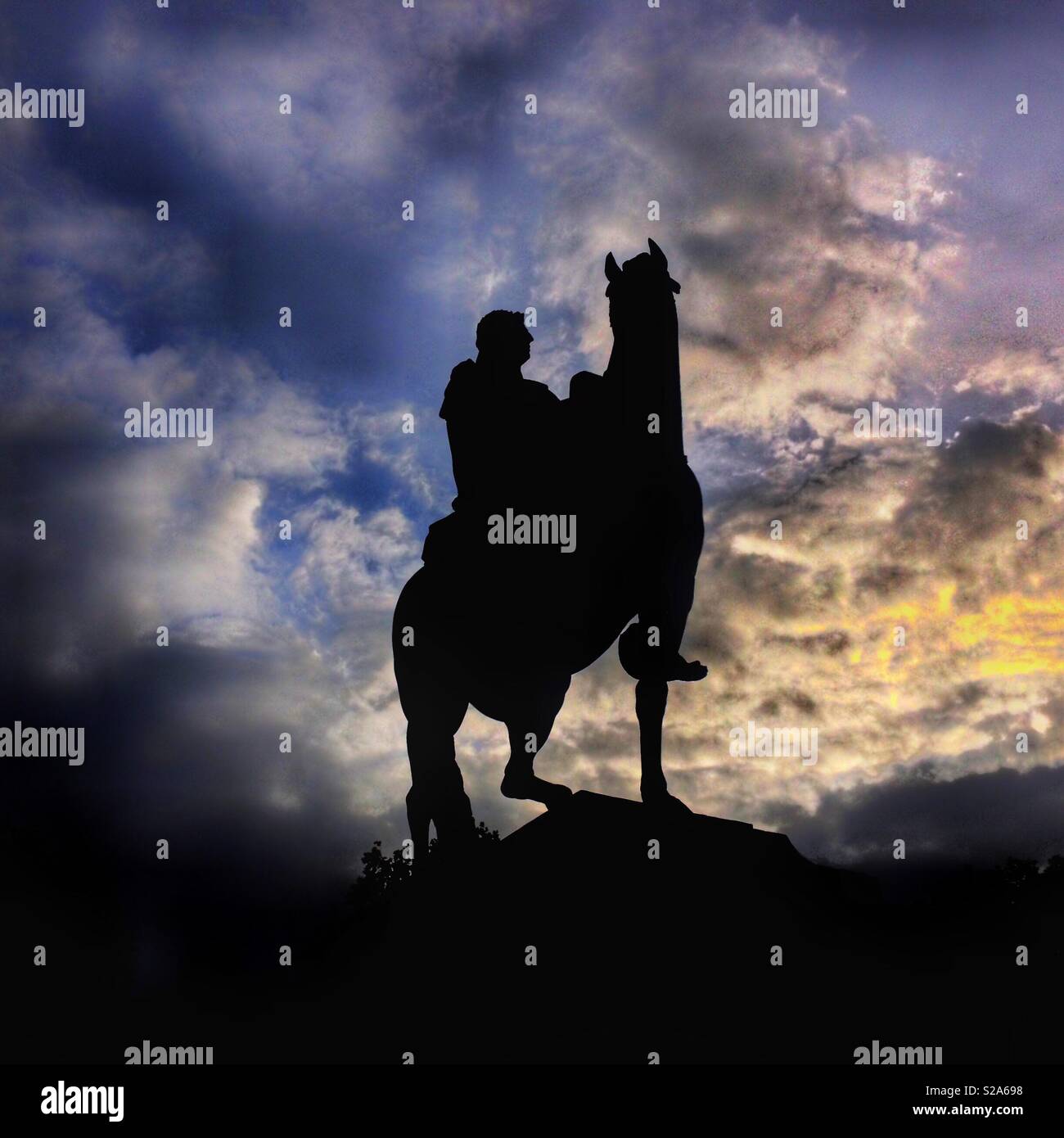 An equestrian statue of William III in Queen Square, Bristol, UK silhouetted against dramatic clouds at sunset - Smartphone Captured Stock Image