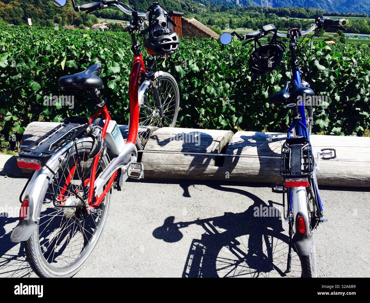 Two E-bikes or bicycles parked outside next to a vineyard in a village in Switzerland Stock Photo