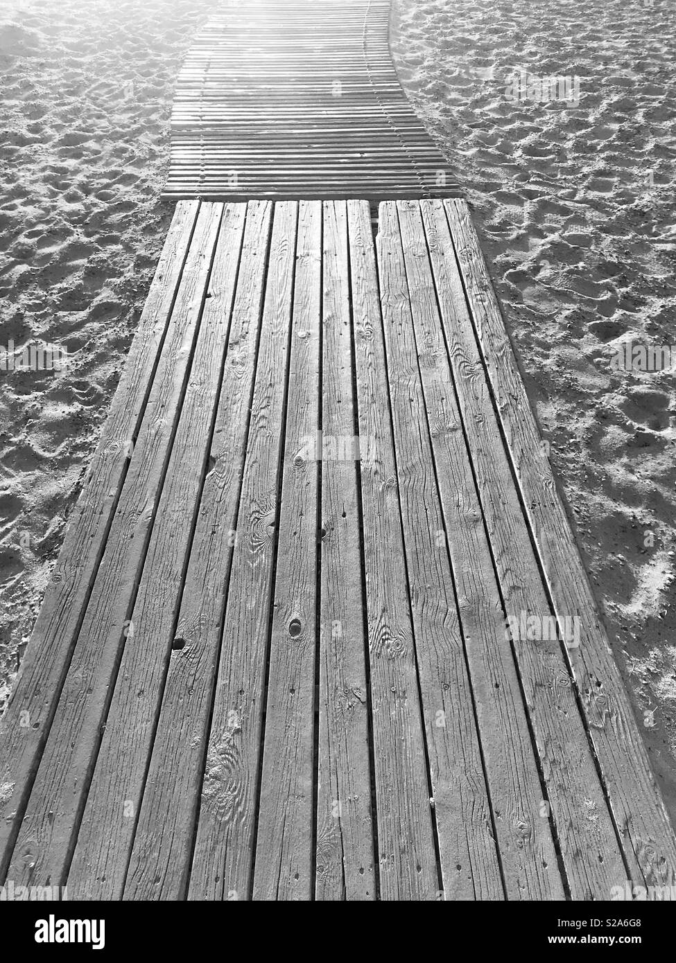 Walk this way - a monochrome image of a boardwalk leading to a sandy beach Stock Photo