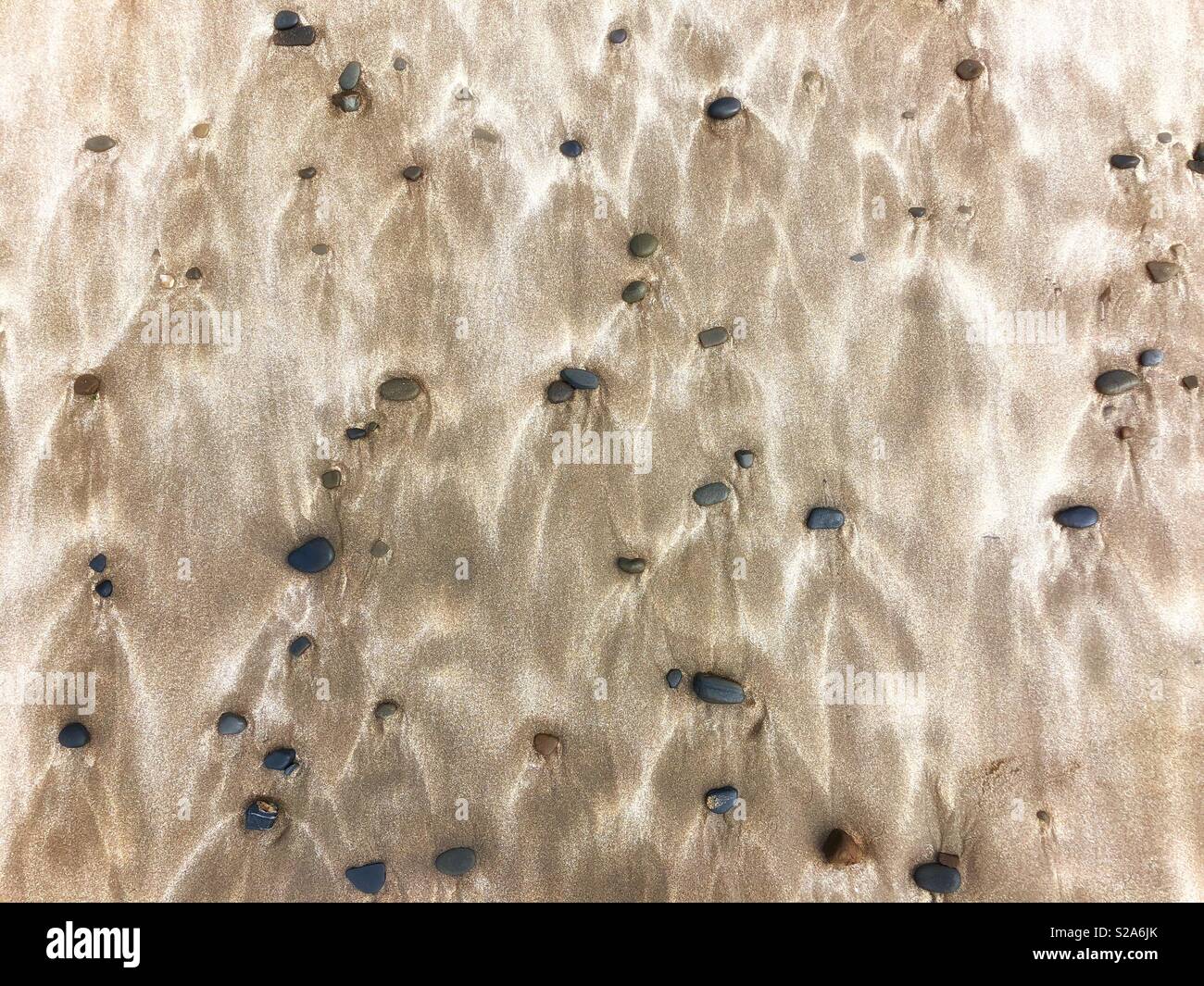 Pebbles and wind blown sand patterns on a Welsh beach. - Smartphone Captured Stock Image