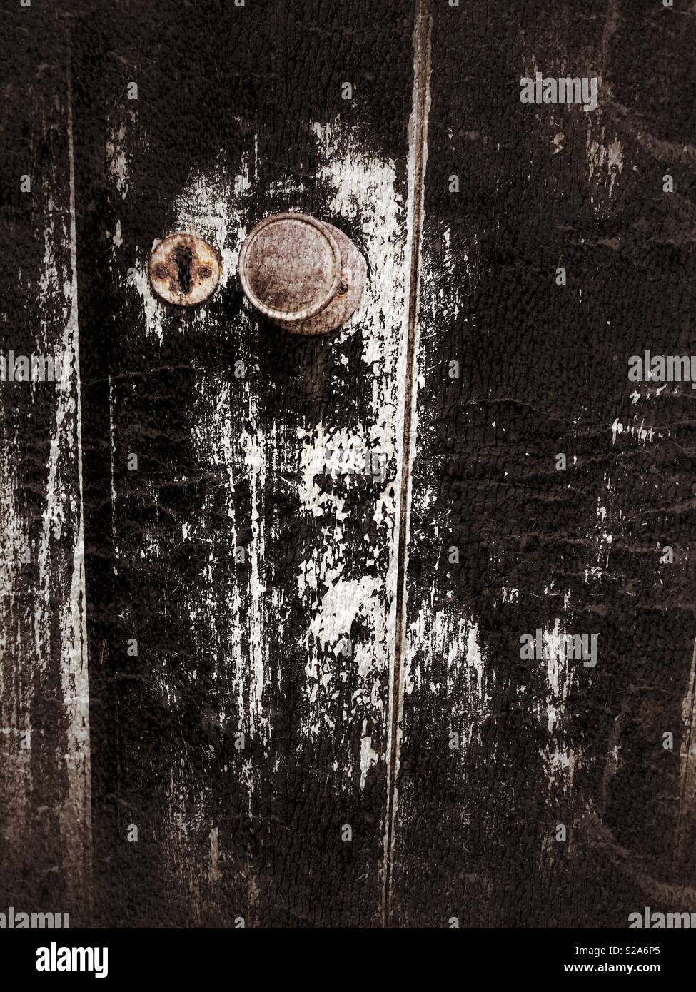 Doorknob on an old black flaking painted door. Stock Photo