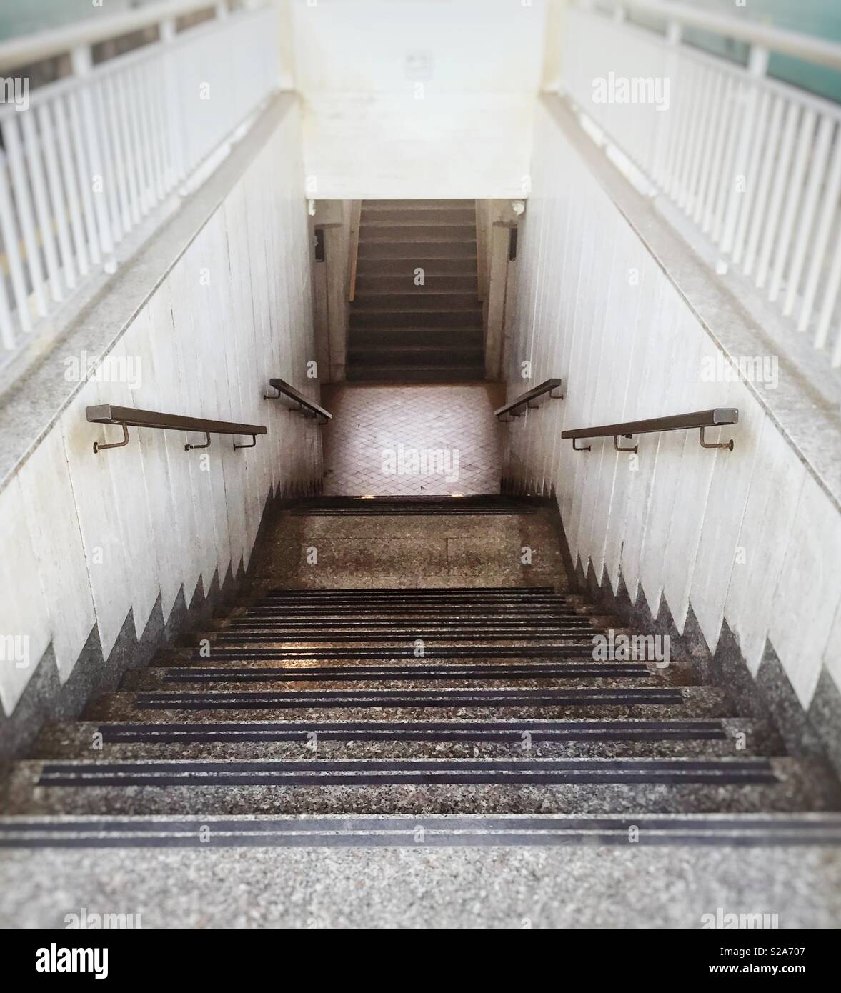 Perspective view of a staircase with iron handrails and with white balustrade - Smartphone Captured Stock Image