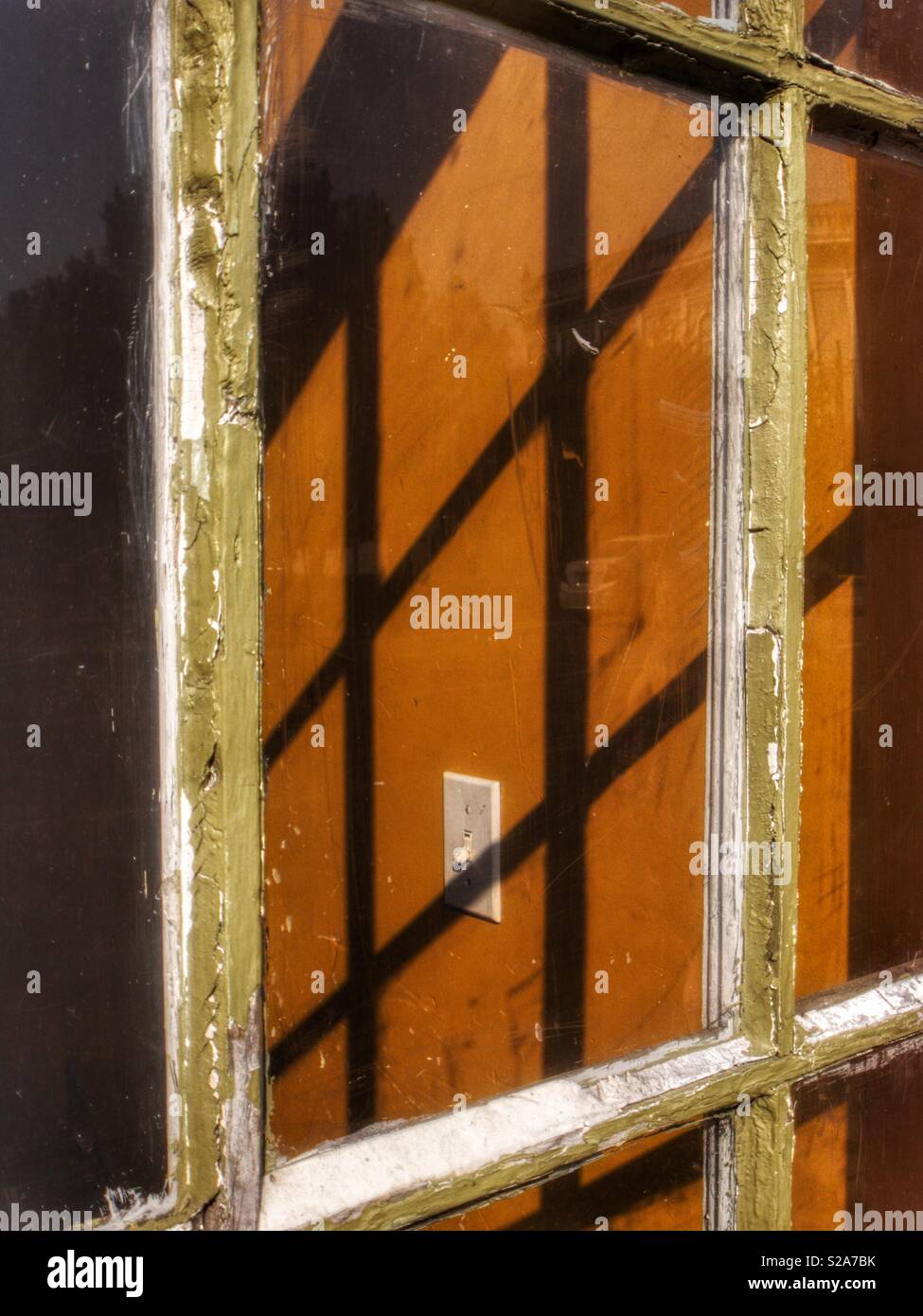 Shadow of window frame on wall with light switch. - Smartphone Captured Stock Image