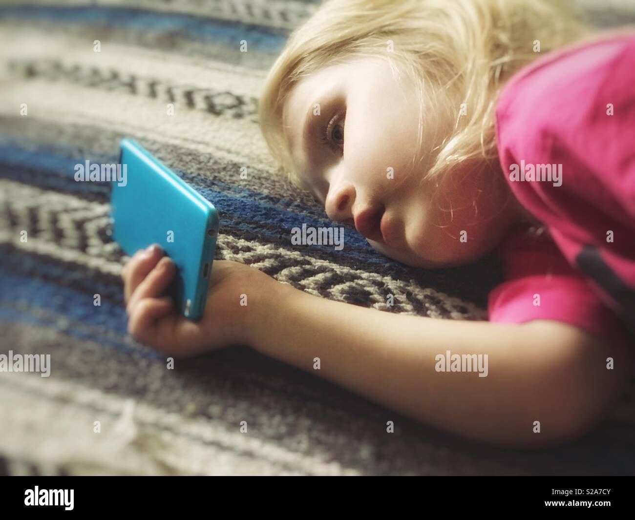 Four year old girl looking at a mobile device Stock Photo