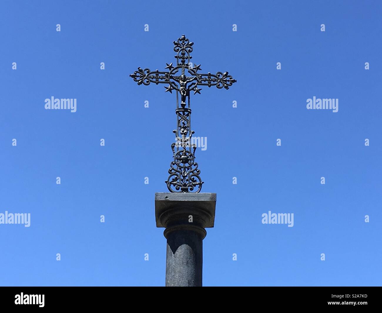 Black metallic ornemental catholic cross on a blue sky Stock Photo