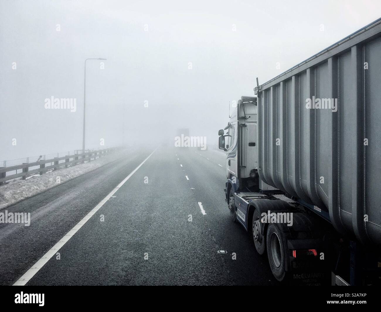 Truck travelling along motorway in thick fog. Stock Photo