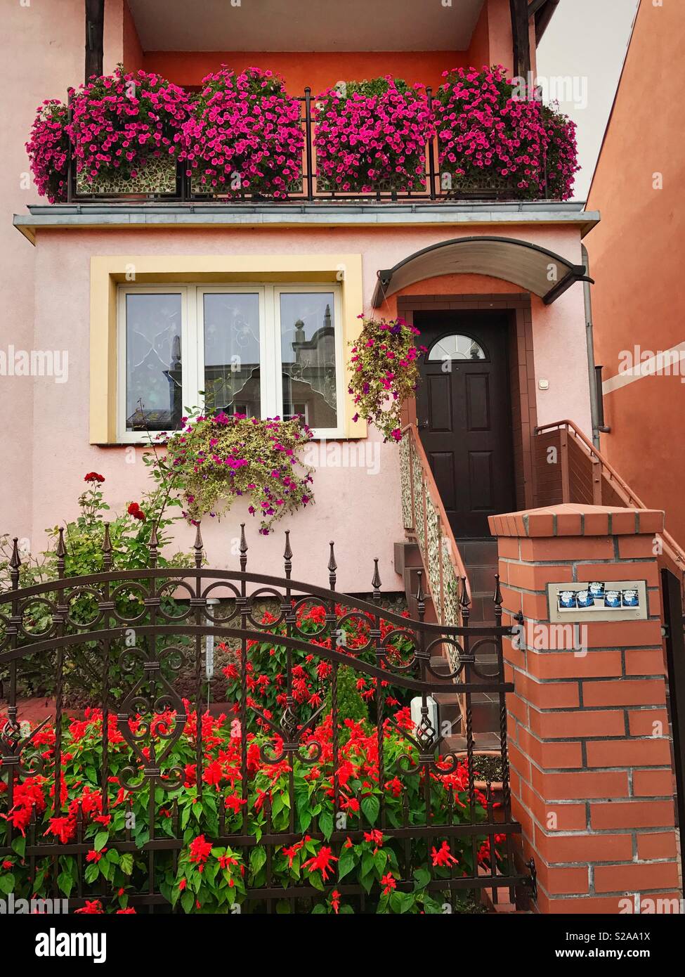 Front of a house with lots of colorful flowers planted in the garden and flower boxes Stock Photo