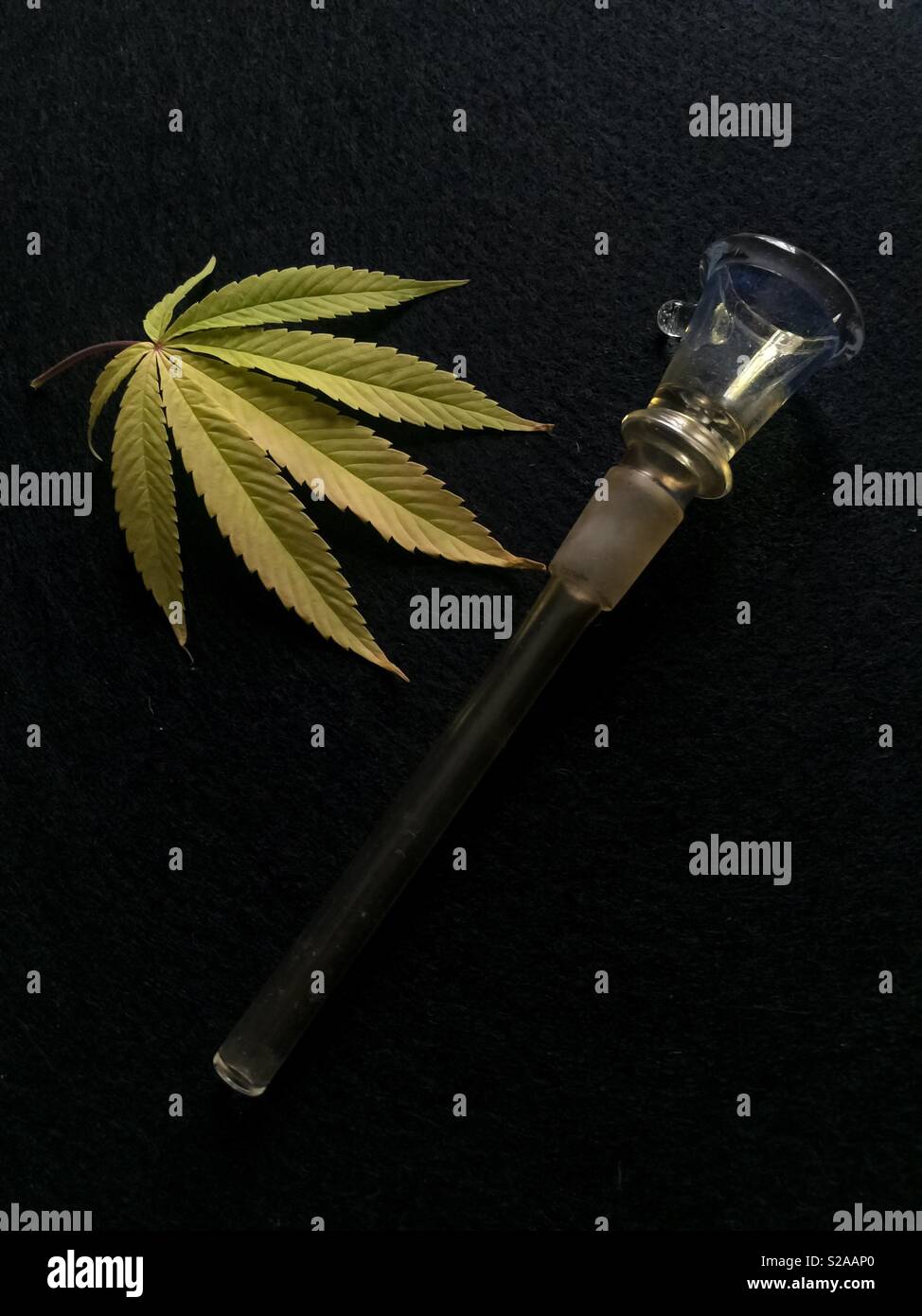 Pot and Pipe: conceptual image for recreational Cannabis  or medical marijuana smoking. Being legalized or decriminalized in many countries and U.S. states. Real leaf. Room for text. Vertical. Stock Photo