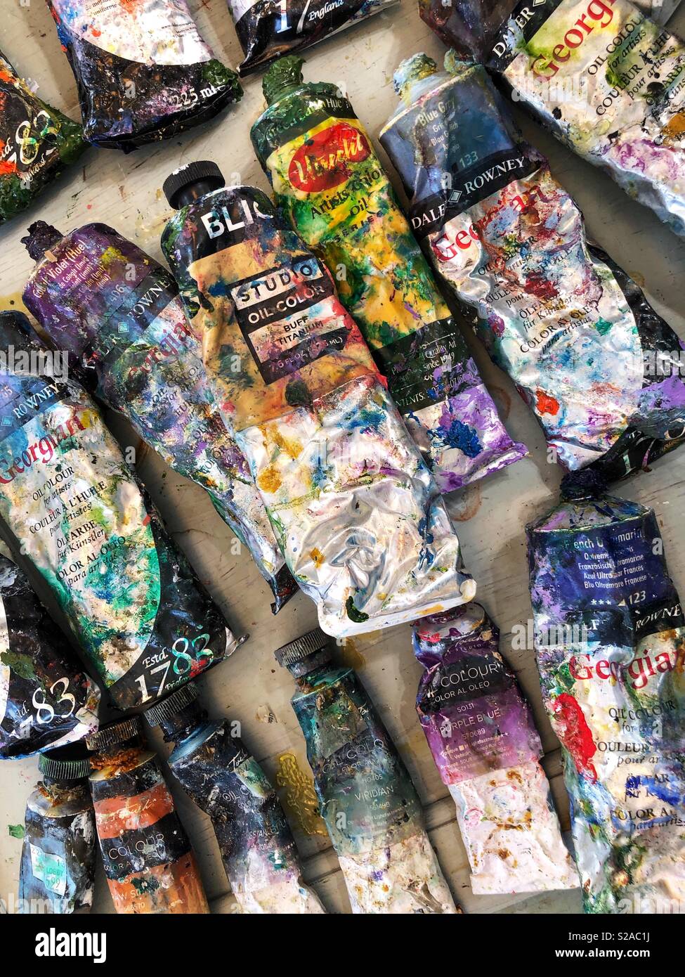 Artist oil paint tubes covered in different colored paints. Stock Photo