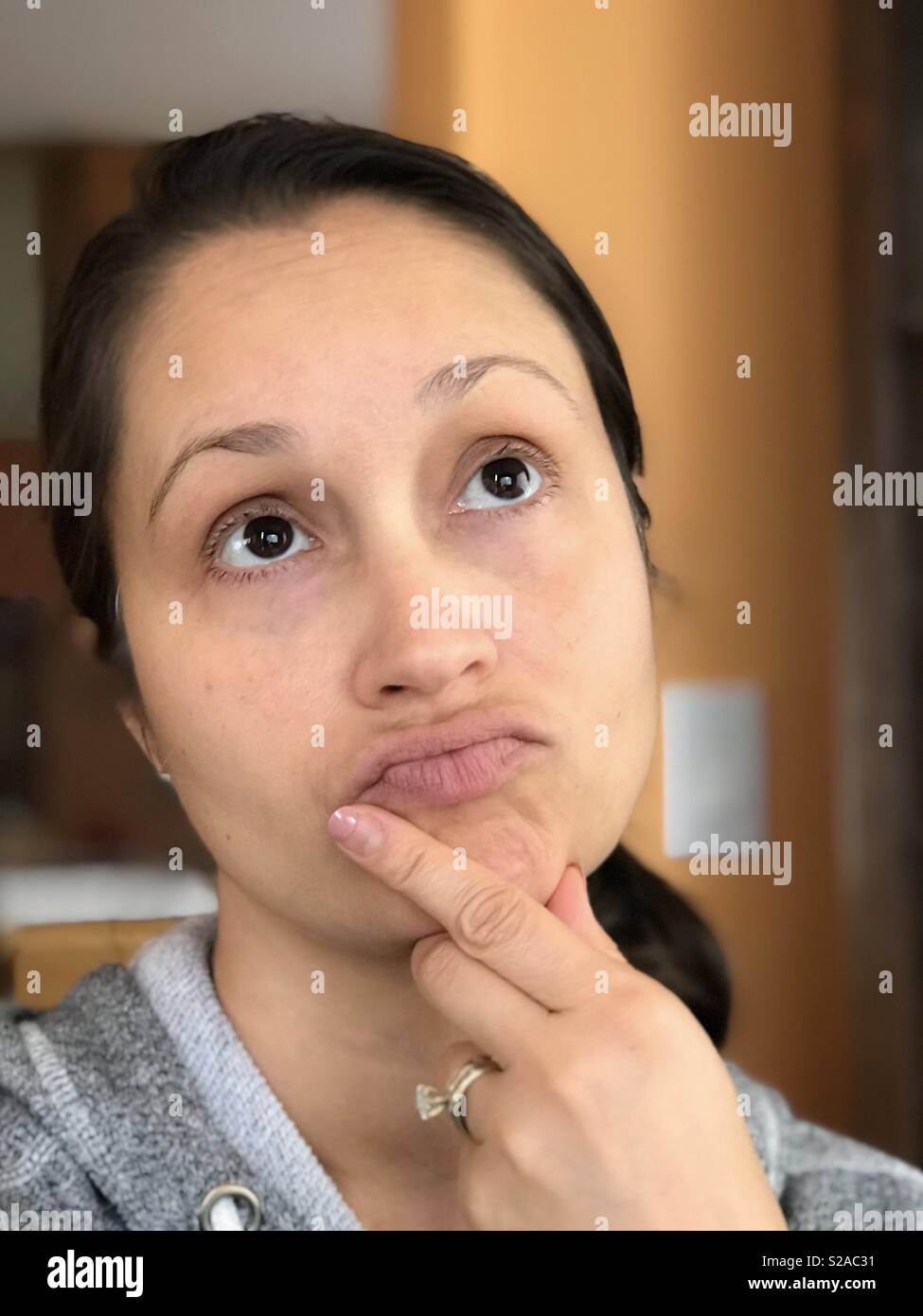 Thinking woman with hand on chin, looking up Stock Photo - Alamy