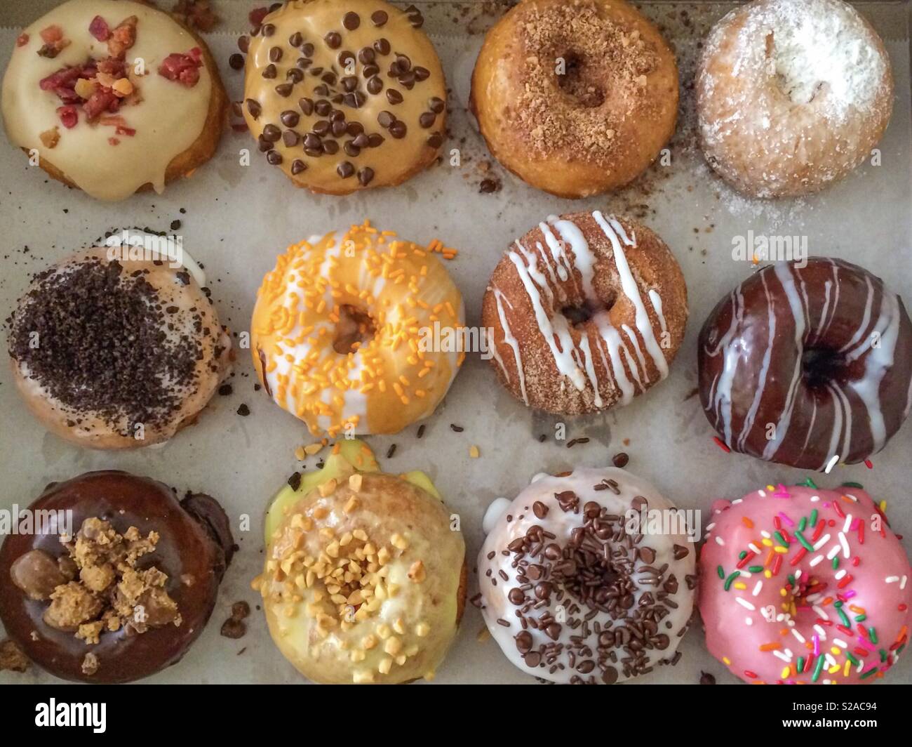 One dozen donuts with glaze and sprinkles multi colored and