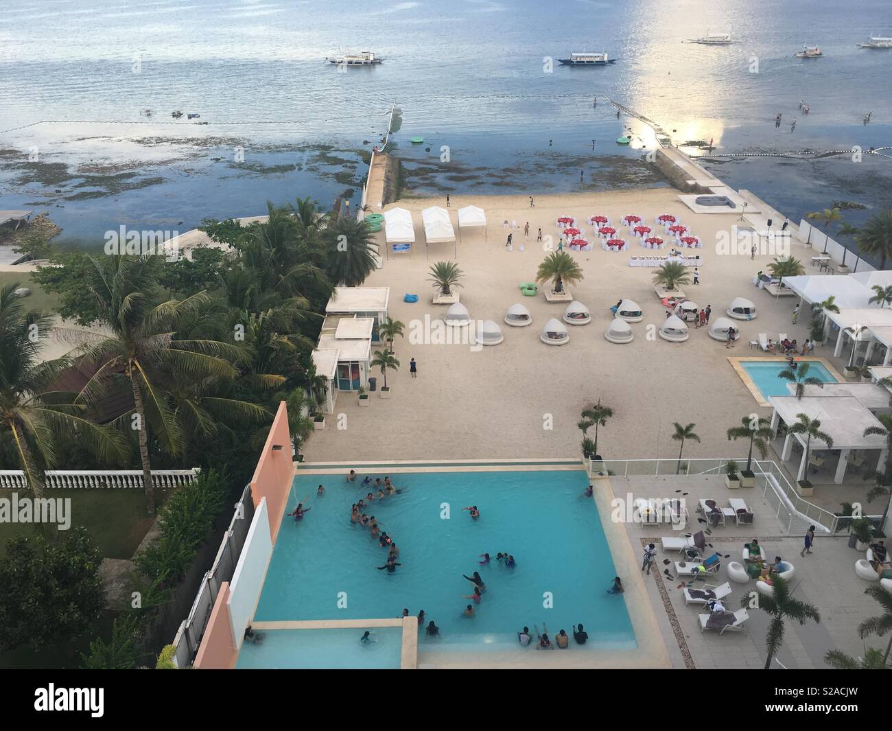 View of a resort with people playing in the pool doing a tango line - Smartphone Captured Stock Image