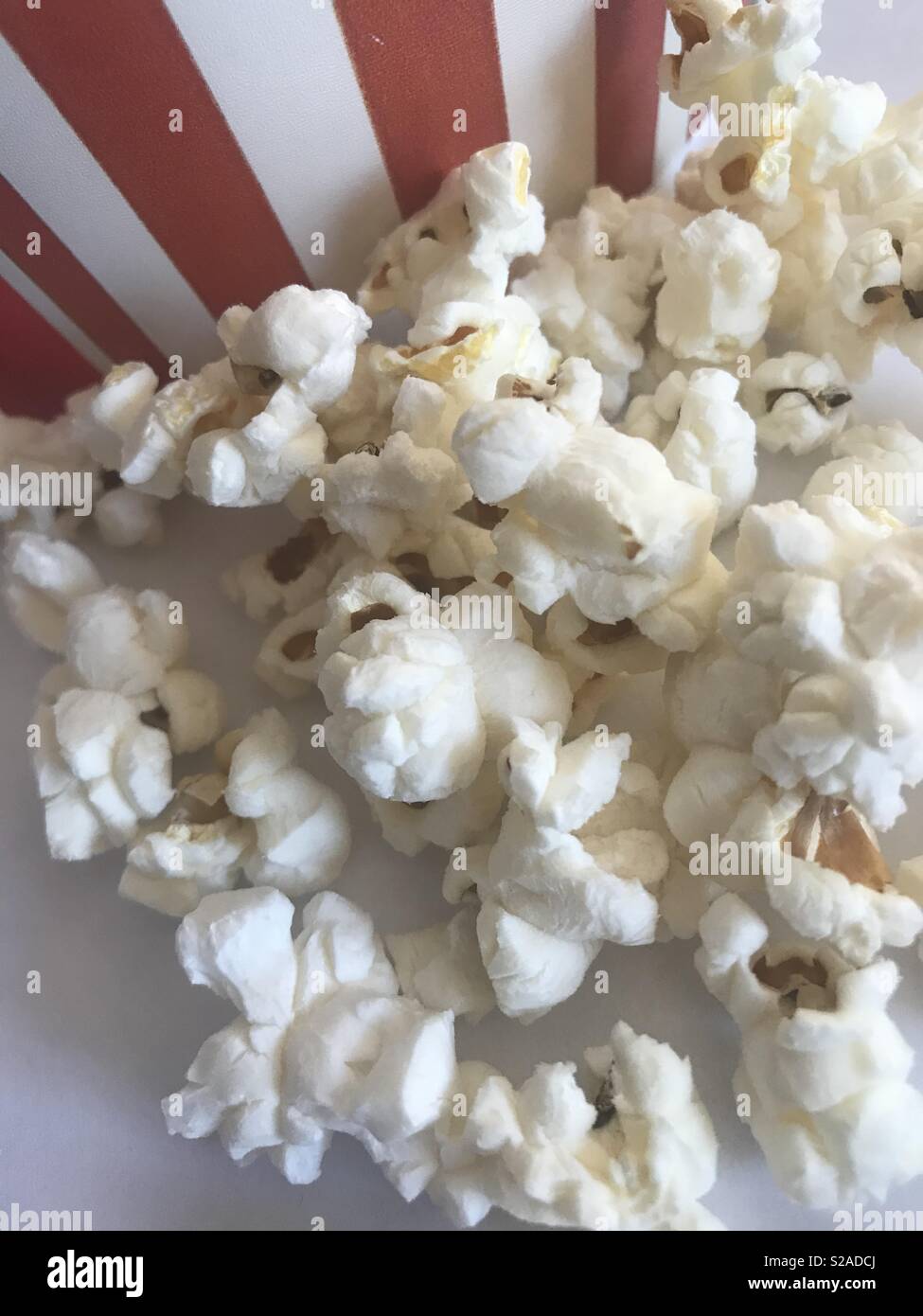 Let’s go to the movies a fun display of white fluffy popcorn sitting in front of a red and white striped bucket Stock Photo