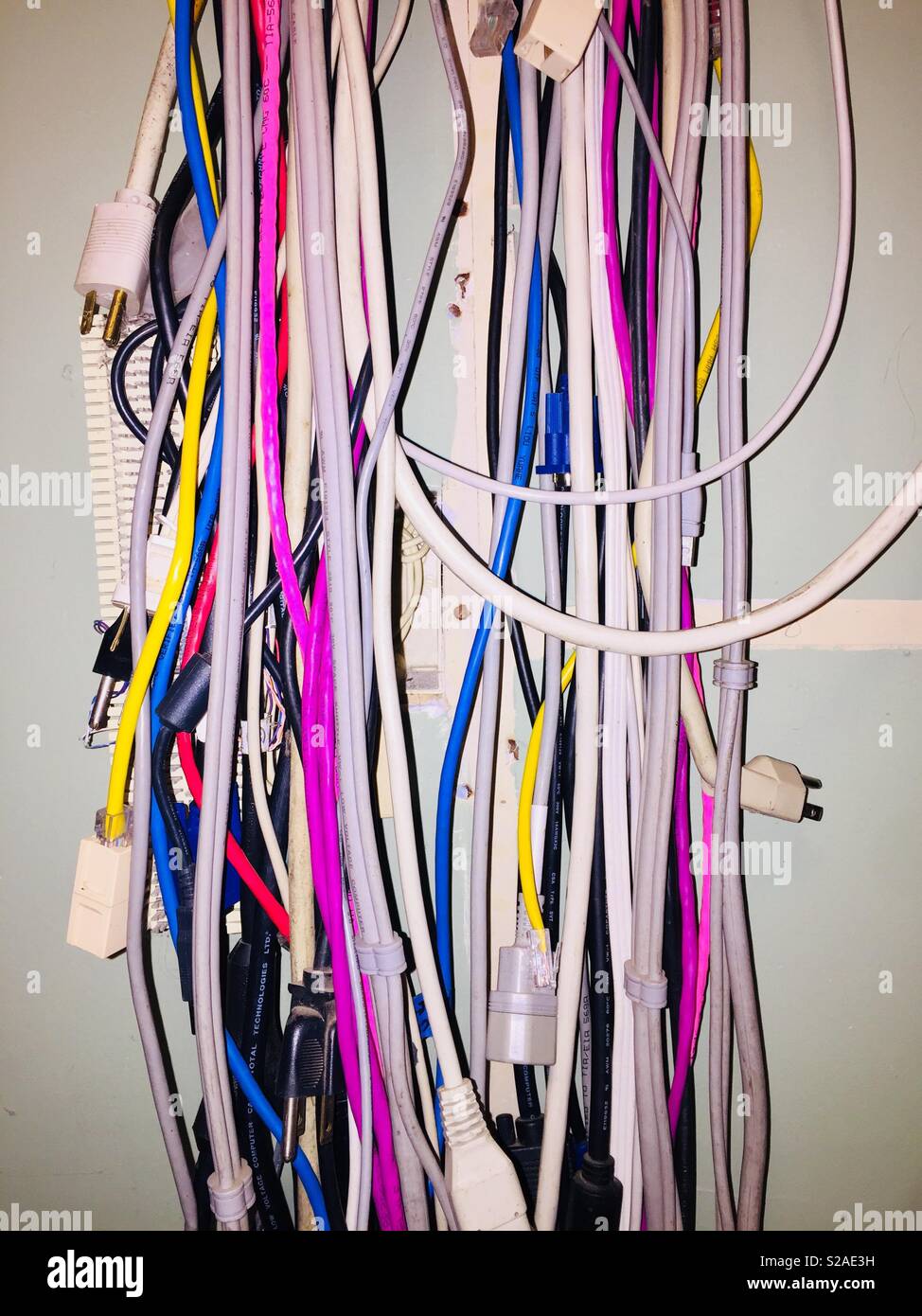 Colorful computer networking and power cords hanging on an unfinished office wall - Smartphone Captured Stock Image