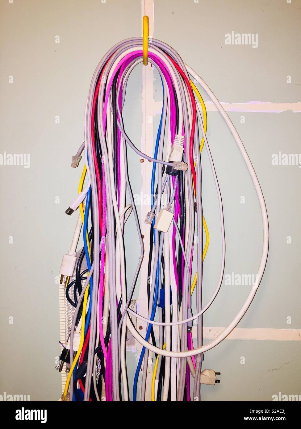 Colorful computer networking and power cords hanging on an unfinished office wall - Smartphone Captured Stock Image