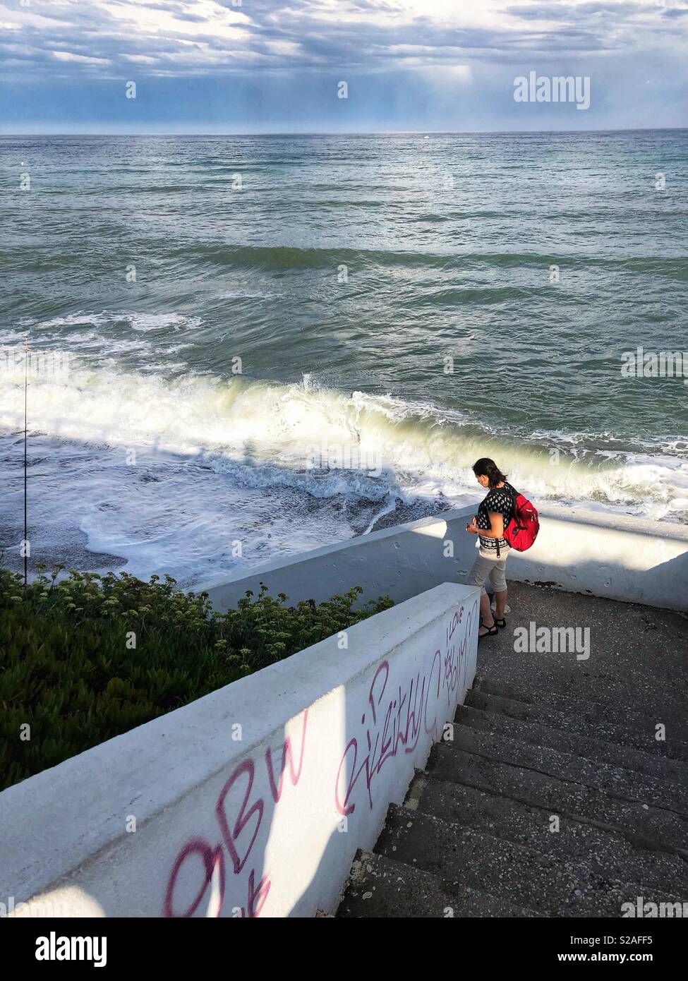 Woman walking down steps to the beach in Fuengirola, Spain. - Smartphone Captured Stock Image