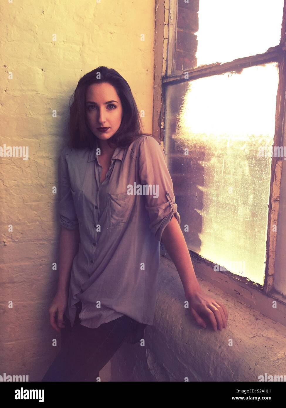 Scared woman standing by the window - Smartphone Captured Stock Image