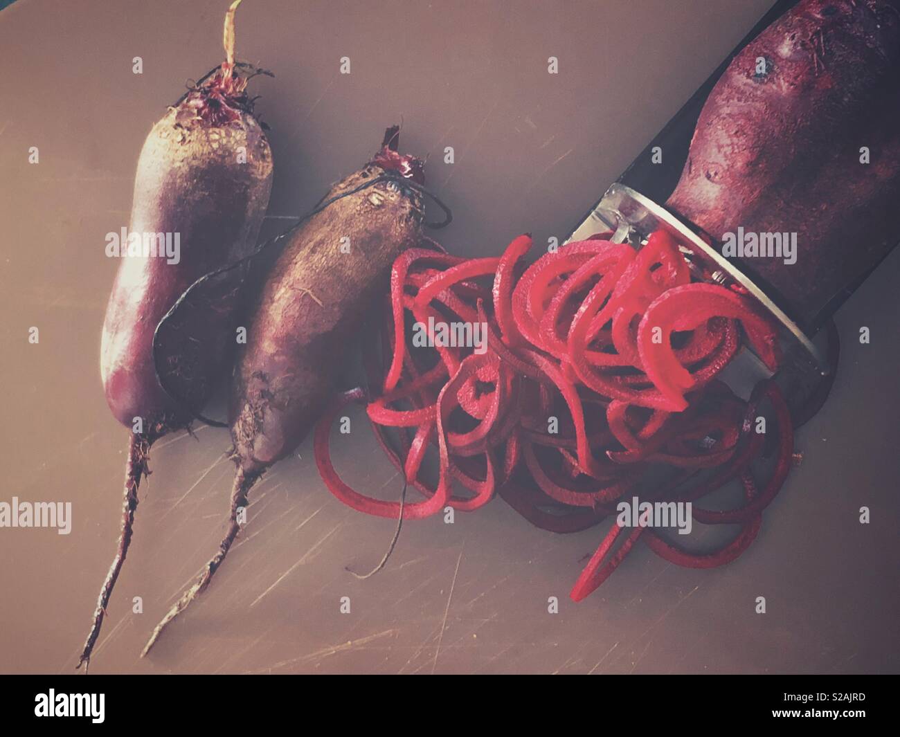 Fresh beet getting spiralized with a spiralizer and two whole beers on the side - Smartphone Captured Stock Image