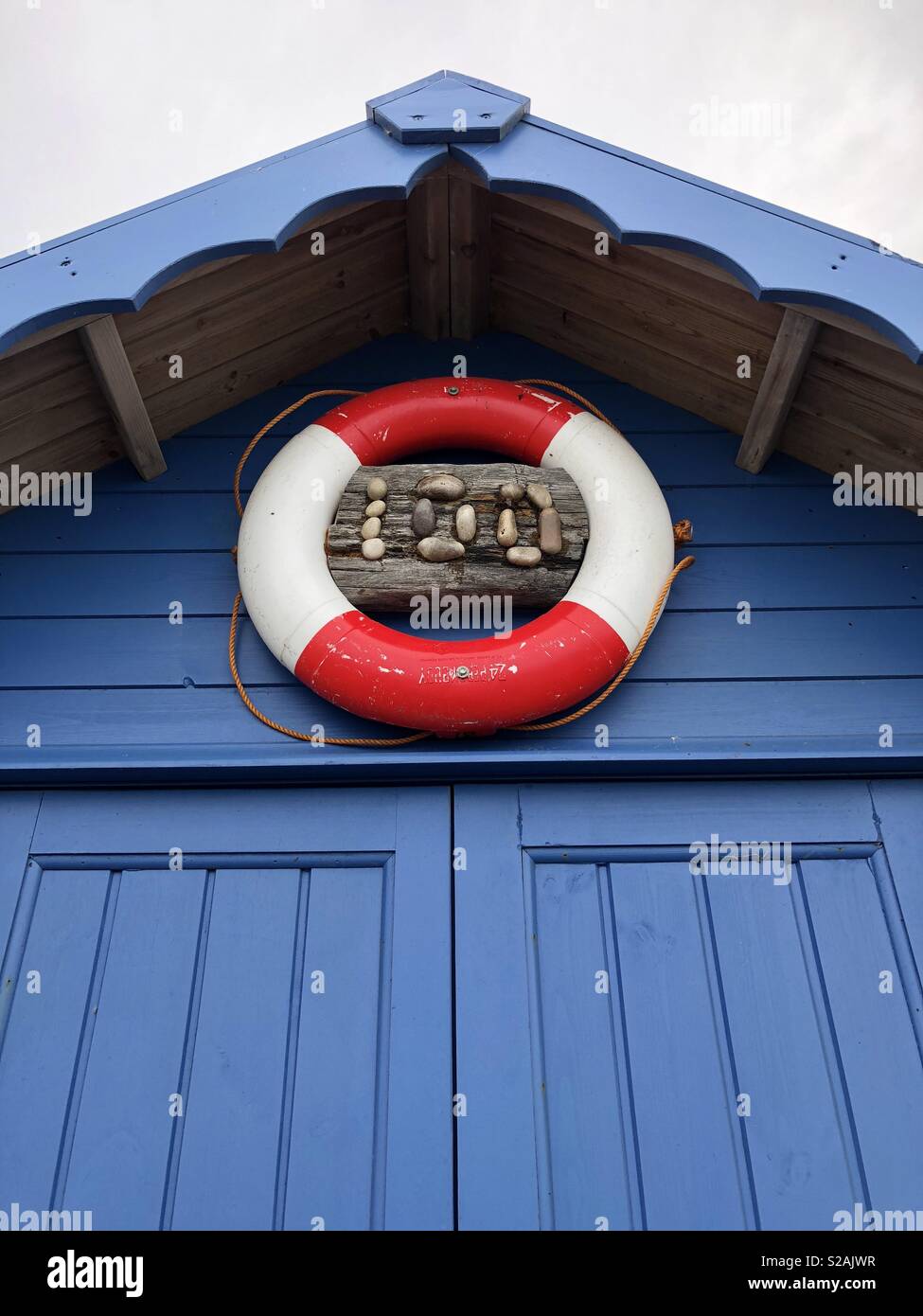Blue beach hut number 100 decorated with a red and white life preserver - Smartphone Captured Stock Image