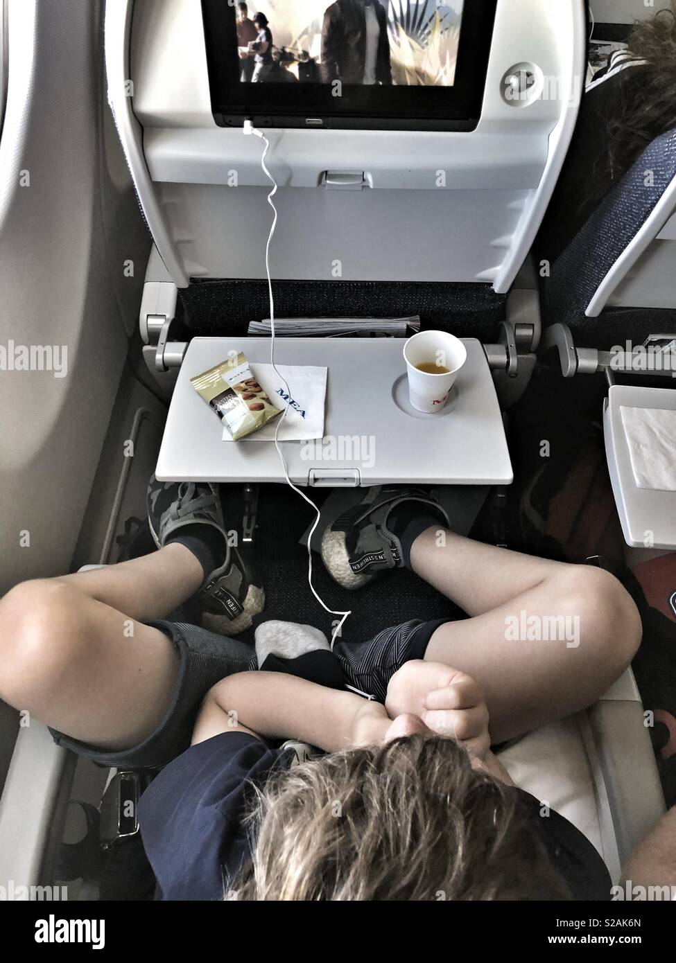 8 years boy watching movie during an airplane flight travel from above - Smartphone Captured Stock Image